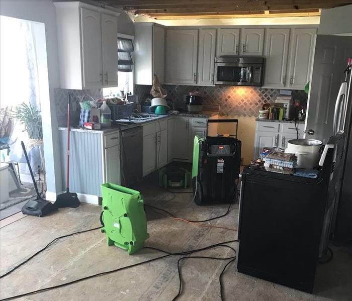 Kitchen with water damage that has dehumidifiers beginning the restoration process.