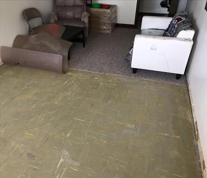 An office space with exposed tile due to water damage that ruined the carpet.