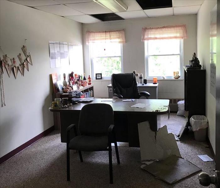 An office with part of the ceiling cracked apart on the desk and floor.